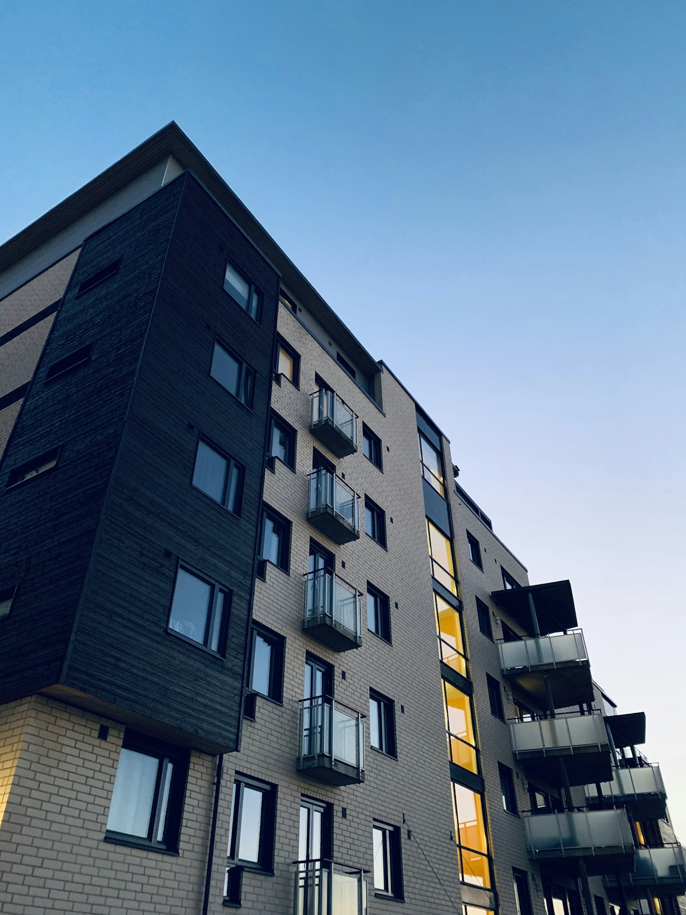 Modern mid-rise condo with glass balconies against a pale sky